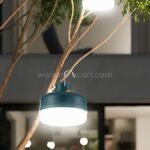 A Rechargeable LED Camping Lantern hanging from a tree branch, glowing brightly in nature.