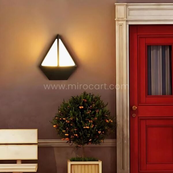 Geometric diamond wall light beside a red door, blending contemporary style with traditional interior design.