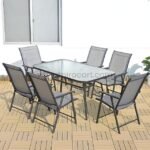 Modern outdoor table set with glass top and foldable chairs placed on a wooden deck.