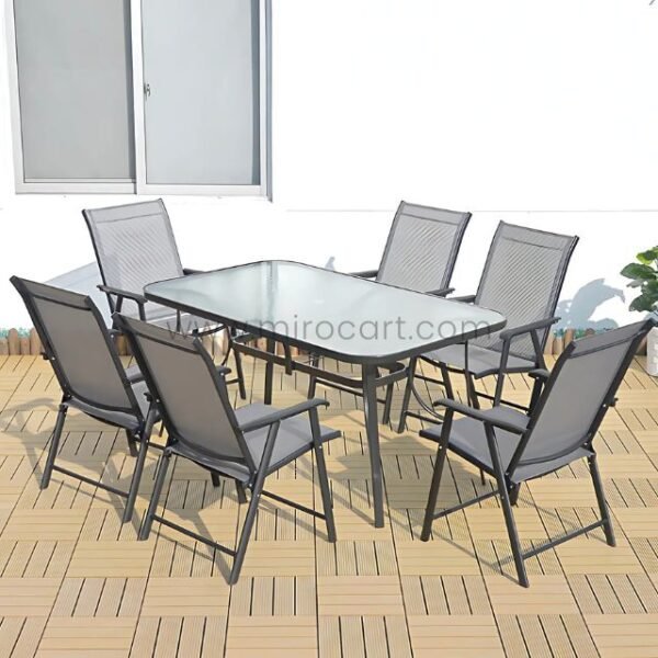 Modern outdoor table set with glass top and foldable chairs placed on a wooden deck.