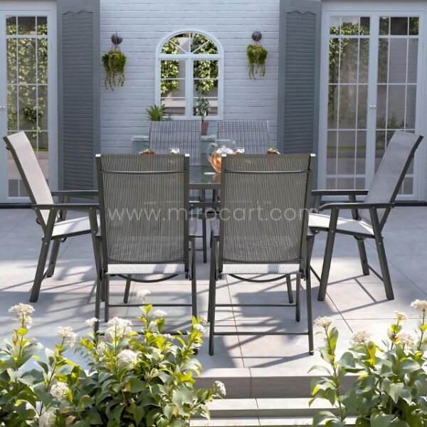 Modern outdoor table set with glass top and foldable chairs in a cozy garden patio.
