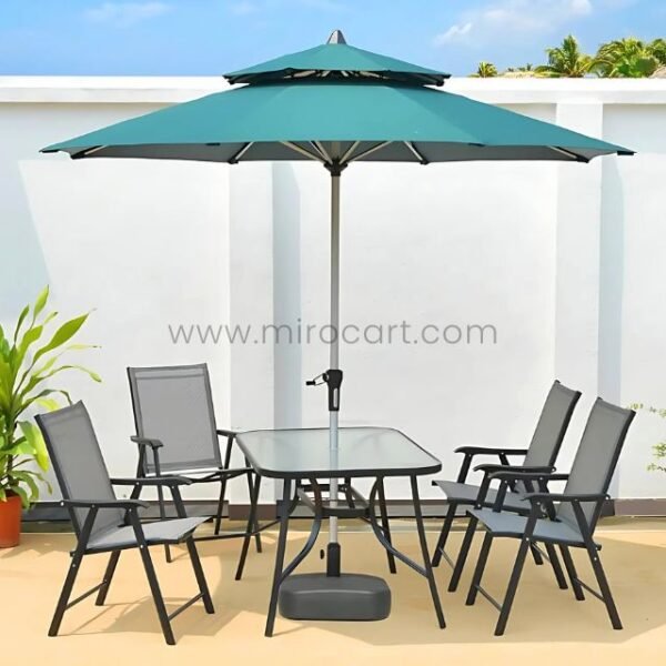 Modern outdoor table set with teal umbrella, glass-top table, and foldable chairs on a sunlit patio