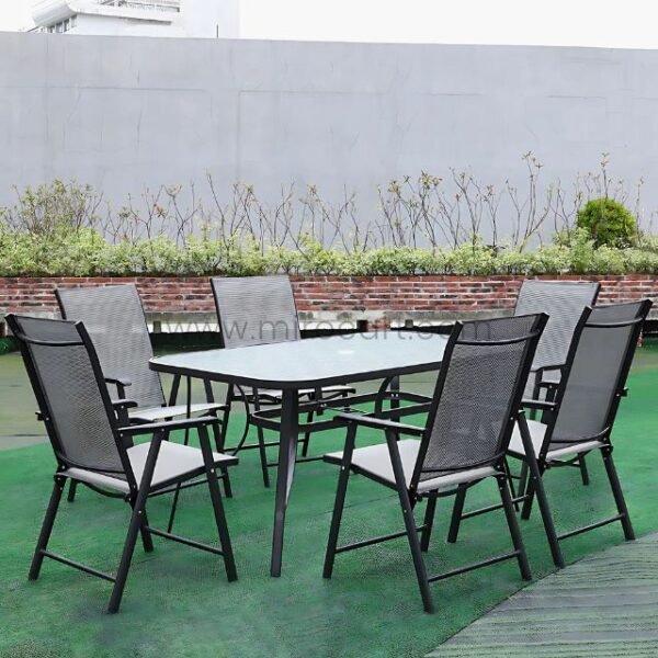 Modern outdoor table set with glass top and foldable chairs on green surface.