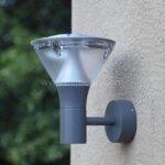 Close-up of a modern outdoor wall light with gray finish mounted on a smooth wall.