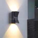 Modern up and down wall light casting warm LED lighting on a pale indoor wall.