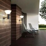 Modern outdoor wall lights mounted on a deck wall, casting ambient light across a cozy outdoor area.