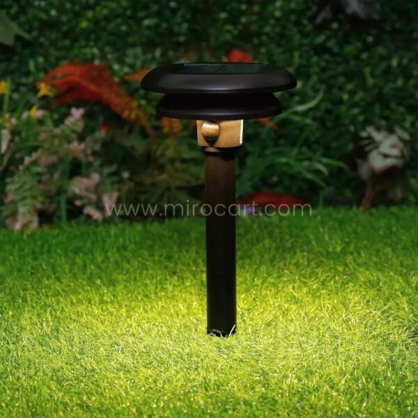 Single solar motion sensor light glowing in a lush flower garden.