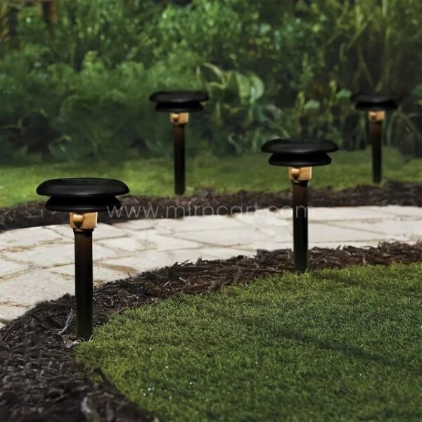 Four solar motion sensor pathway lights installed along a garden path, casting warm illumination.