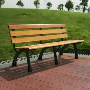 Classic wooden park bench with a light brown solid wood seat and black metal frame, situated on a red composite deck overlooking a green lawn.