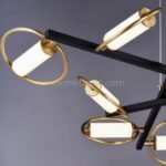 Close-up of Modern Cross Pendant Chandelier showing black frame, gold rings, and glowing opal acrylic tubes.