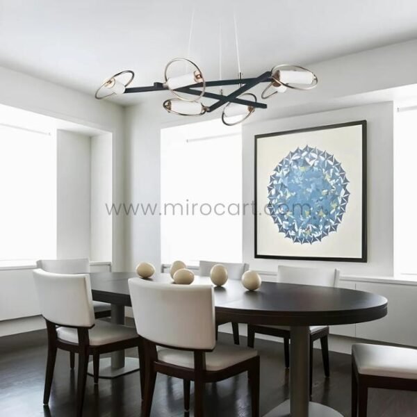 Modern Cross Pendant Chandelier above dark wood dining table with white chairs and geometric wall art.