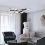 Modern Cross Pendant Chandelier above curved sofa and coffee table in a minimalist living room.